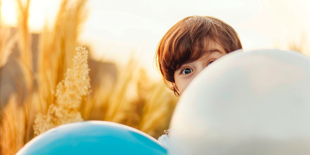 boy-peeking-behind-balloons