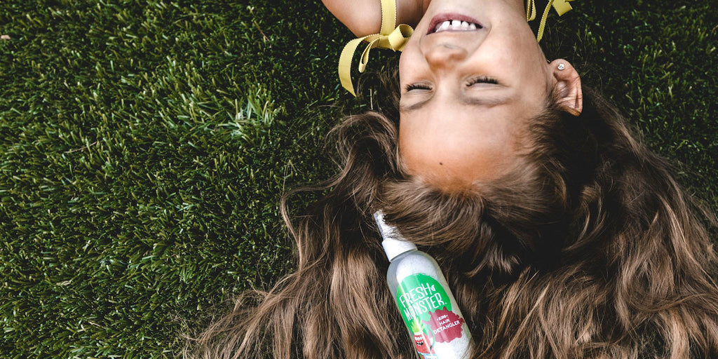 Child_Smiling_On_the_Ground_With_Hair_Detangler